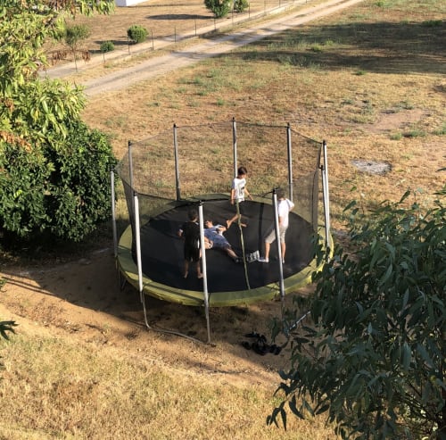 Enfants jouant sur un trampoline à VillaSerenita à Alata, France, avec terrain rural et végétation