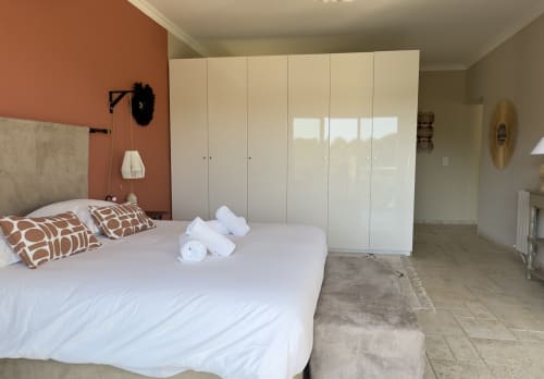 Chambre moderne de la VillaSerenita Ajaccio avec lit queen-size, armoire blanche et mur d'accent en terre cuite