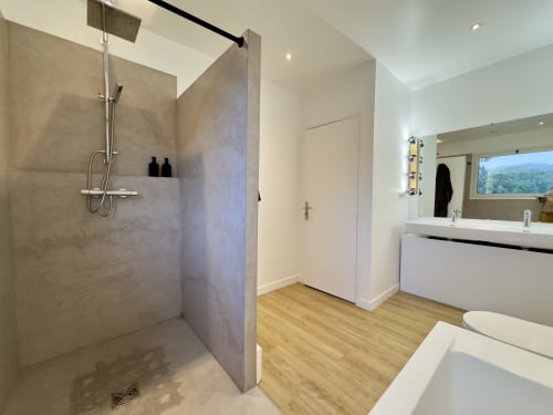 Salle de bain moderne à VillaSerenita à Alata avec douche spacieuse, baignoire, double vasque, toilettes et sol en bois