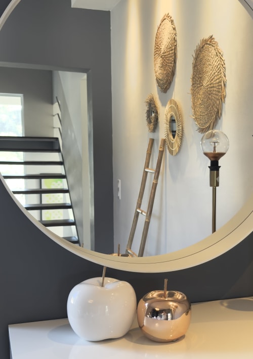 Entrée élégante de La Villaserenita avec miroir rond, éléments muraux tissés et accessoires modernes