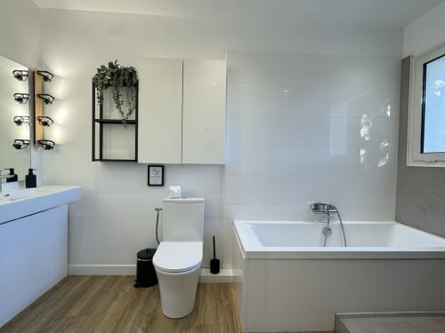 Salle de bains moderne de la VillaSerenita Alata avec meuble-lavabo, toilettes, baignoire et appliques