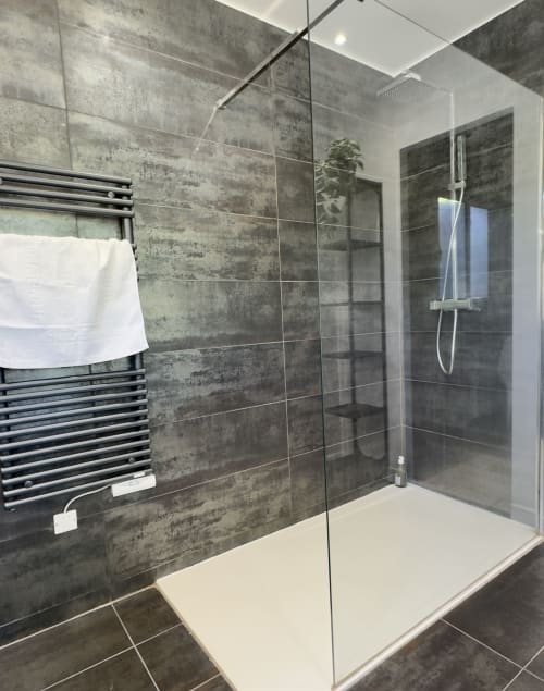 Salle de bain moderne à à VillaSerenita Alata avec douche à l'italienne, carrelage gris, porte-serviettes chauffant et équipements blancs