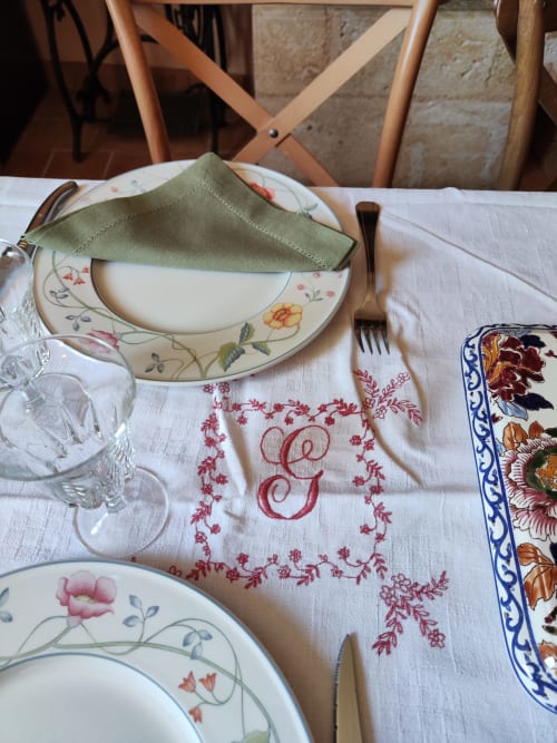 Élégant couvert à Le Rêve d'Alice avec assiettes fleuries, serviette verte et linges de table brodés à Saint-Puy