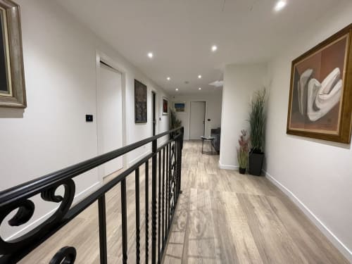 Corridoio moderno dell'hotel Saint Michel a Gorizia con ringhiera nera, pavimenti in legno e opere d'arte contemporanea