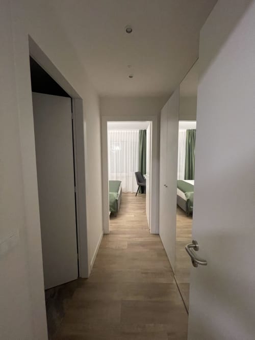 Corridoio dell'hotel Saint Michel Gorizia con pareti bianche, pavimento in legno e porte che conducono alle camere con vista sulla città