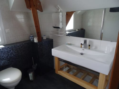Salle de bain moderne avec lavabo blanc, carrelage noir, miroir et toilettes au B&B CafecouetBreizh à Guipry-Messac