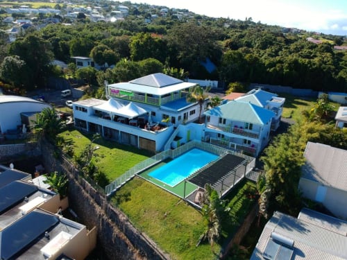 Vue aérienne de l'Hôtel le soleil couchant à Saint-Pierre, La Réunion avec piscine bleue, jardins verdoyants et bâtiments blancs
