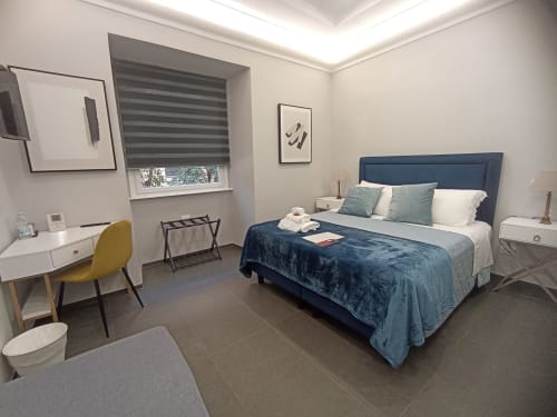 Modern bedroom at AD Trastevere Guest House Rome with blue bed, desk, striped window shade, and contemporary decor