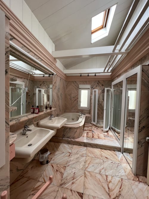 Baño de lujo en marmolados rosa con doble lavabo, ducha walk-in, tragaluz y toalleros en los Chalets Junto A Puy Du Fou Arges, Toledo, España.