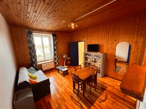Intérieur chaleureux du cottage en bois du Restaurant du Port avec table à manger, lit et vue sur le lac