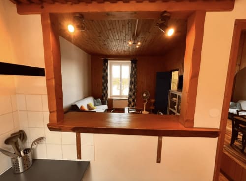 Chambre chaleureuse du Restaurant du Port avec poutres apparentes, fenêtre donnant sur le lac et espace de vie ouvert