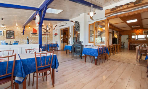 La salle à manger du Restaurant du Port à Saint Pierre de Boeuf avec nappes bleues, chaises en bois et décoration nautique
