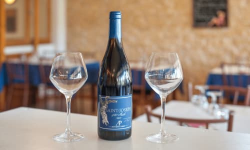 Bouteille de vin Saint-Joseph avec deux verres vides au Restaurant du Port, Saint-Pierre-de-Boeuf
