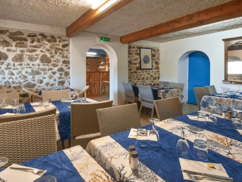 Salle à manger du Restaurant du Port à Saint Pierre de Boeuf : murs en pierre, chaises tressées et touches de bleu