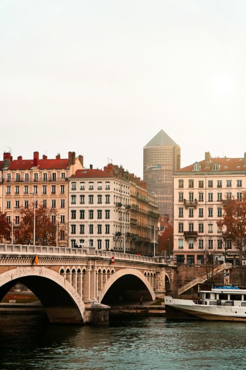 Pont historique français enjambant une voie d'eau avec bâtiments parisiens colorés et bateau fluvial près du Restaurant du Port