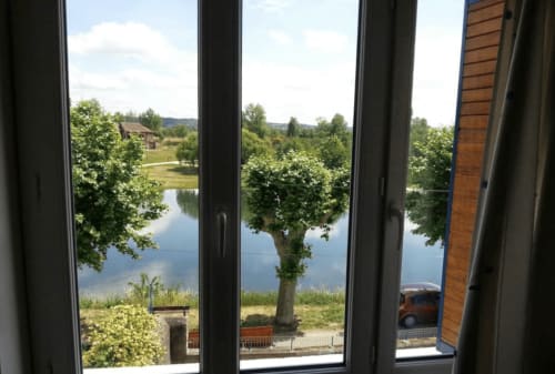 Vue sur le lac depuis les fenêtres du gîte au Restaurant du Port, Saint-Pierre-de-Bœuf, avec arbres et paysage de rive