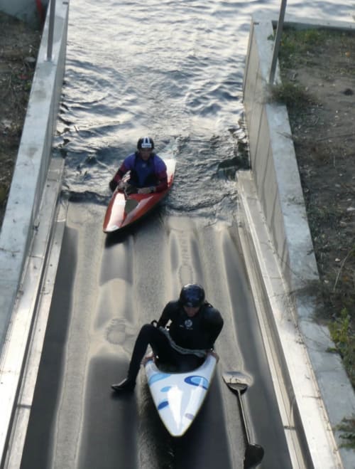 Deux kayakistes naviguant dans un étroit chenal aquatique près du Restaurant du Port, Saint Pierre de Boeuf