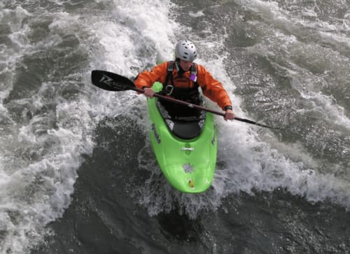 Kayakiste en eaux vives dans un kayak vert vif naviguant les rapides près de Saint Pierre de Boeuf