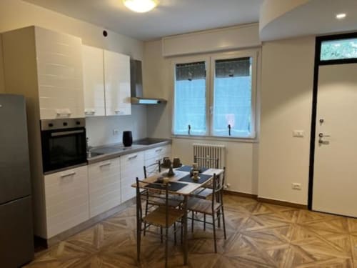 Moderna kuhinja-blagovaonica u apartmanu EmilBo' House u San Lazzaro di Savena s bijelim ormarima, crnim stolom i vrtom