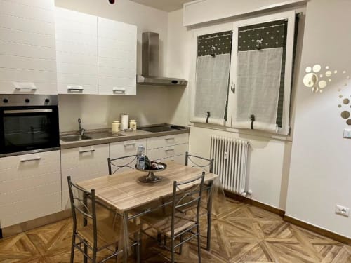 Modernog kuhinja i blagovnica u apartmanu EmilBo' House, San Lazzaro di Savena s bijelim ormarima i pogledom na vrt