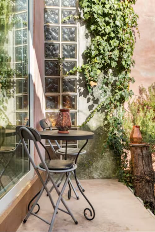Cozy terrace seating area at CasaRosada B&B in Vidracco, Italy, surrounded by climbing ivy and large windows