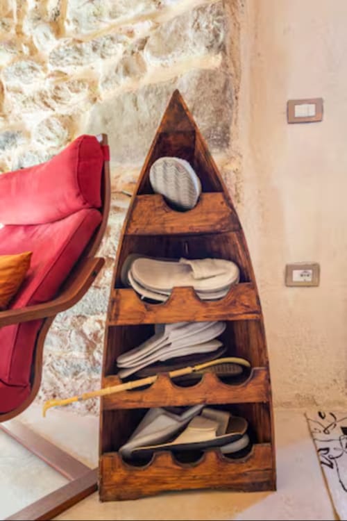 Wooden boat-shaped shelving unit with white linens at CasaRosada B&B in Vidracco, Italy