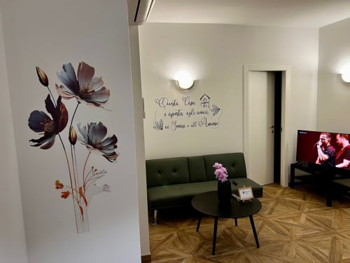 Dnevna soba apartmana EmilBo' House s cvjetnom zidnom umjetnošću, zelenim sofom i pogledom na vrt u San Lazzaro di Savena