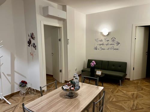 Dnevni boravak apartmana EmilBo' s drvenim parkétom, zelenom sofom, blagavnom s trijemom i talijanskom zidnom dekoracijom