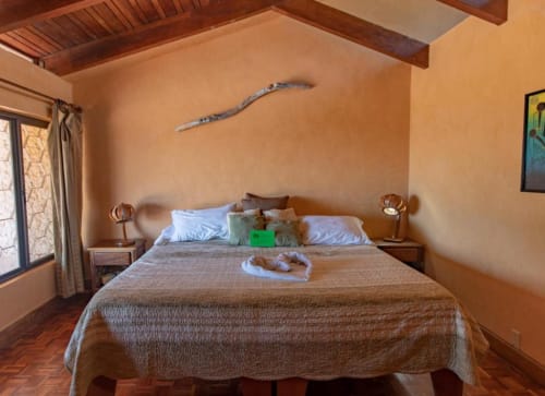 Tortuga room at Villa Mango B&B in Nosara with warm terracotta walls, wooden beams, and sea view in Costa Rica