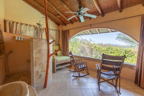 Congo room at Villa Mango B&B in Nosara with garden views, modern bathroom, wooden ceiling, and furnished balcony