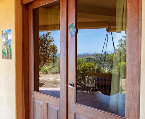 Open wooden doors to Iguana room garden at Villa Mango B&B in Nosara, Costa Rica, with ocean views