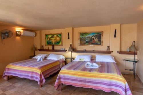 Spacious double bedroom at Villa Mango B&B in Nosara with colorful striped bedding, garden views, and rustic décor