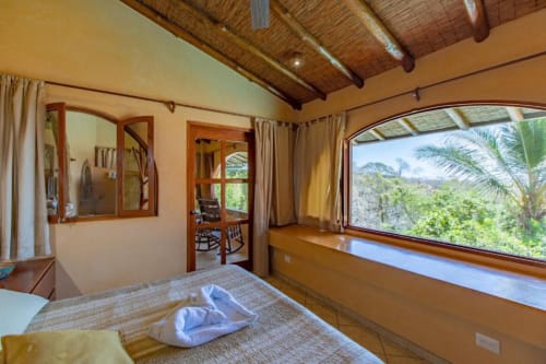 Congo room at Villa Mango B&B in Nosara with garden view, wooden beams, and large windows overlooking tropical vegetation