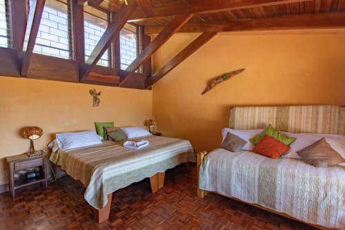 Spacious Rana room at Villa Mango B&B in Nosara with two beds, wooden beams, skylights, and warm orange walls