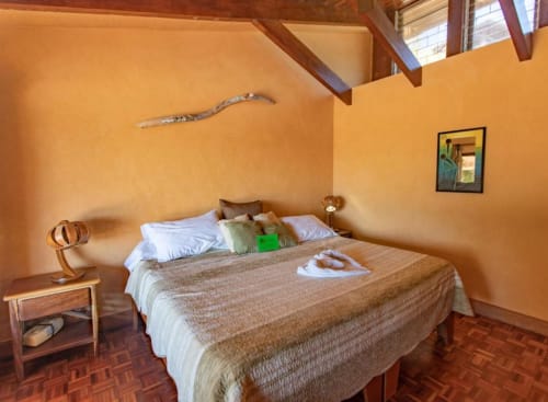 Tortuga room at Villa Mango B&B in Nosara with orange walls, wooden beams, and sea view bedroom
