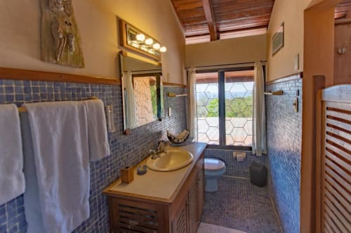 Tortuga room bathroom at Villa Mango B&B in Nosara with blue tile, wooden vanity, and ocean view doors