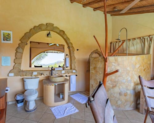 Congo room bathroom at Villa Mango B&B in Nosara with stone archway, round sink, and garden view window