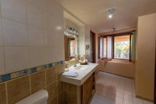 Spacious bathroom in Iguana room at Villa Mango B&B, Nosara, featuring double vanity, tiled walls, and garden views