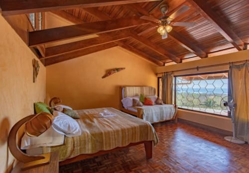 Spacious Rana room at Villa Mango B&B in Nosara with two beds, wooden beams, and ocean views