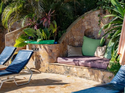 Tropical garden seating area at Villa Mango B&B in Nosara with lounge chairs and cushioned bench