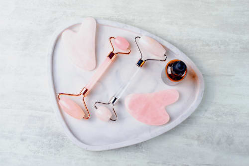 Rose quartz facial rollers and gua sha tools on marble tray at Belloréade B&B in Belloc, France
