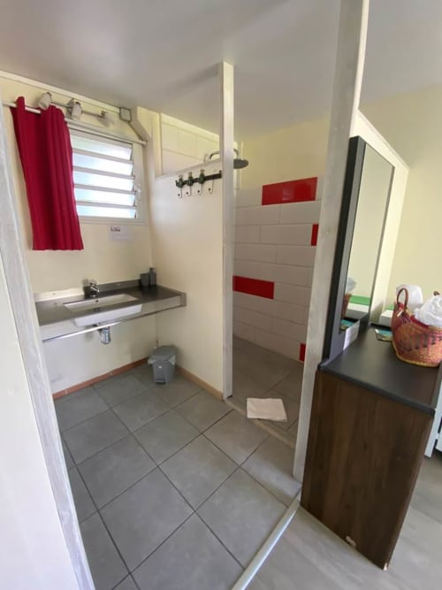 Salle de bain moderne avec douche, lavabo et touches de rouge à l'Hôtel le Soleil Couchant, Saint-Pierre Réunion