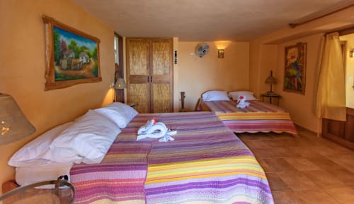 Colorful bedroom at Villa Mango B&B in Nosara with two beds, striped bedding, and garden view artwork