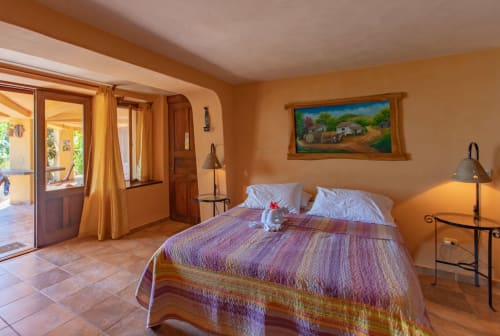 Bright bedroom at Villa Mango B&B in Nosara with colorful bedding, terracotta tiles, and garden views through French doors