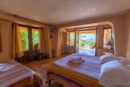 Spacious bedroom at Villa Mango B&B in Nosara with two beds, garden views, and terrace access