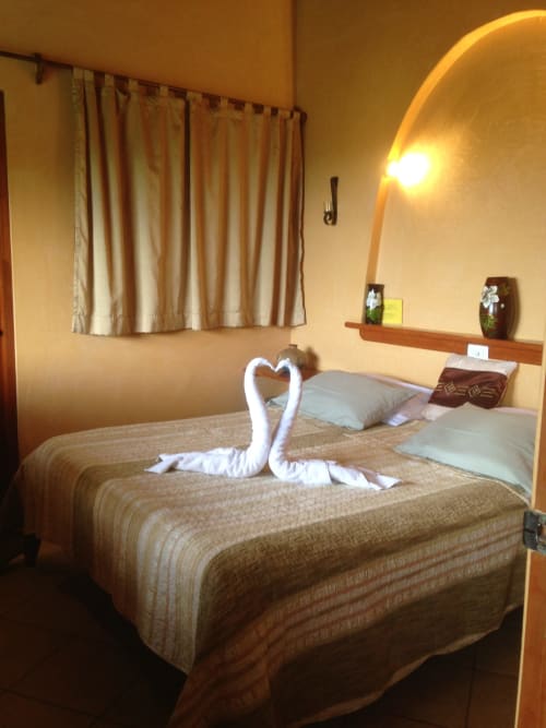 Cozy bedroom at Villa Mango B&B in Nosara with white swan towel sculpture on bed, warm lighting, and garden view