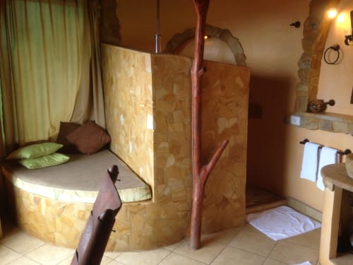 Pizote room at Villa Mango B&B in Nosara with curved bed, stone walls, and garden view