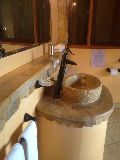 Luxurious bathroom at Villa Mango B&B in Nosara with stone vessel sink, black fixtures, and large mirror