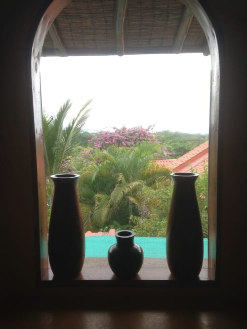 View from Pizote room at Villa Mango B&B in Nosara showing three black vases on terrace overlooking lush tropical garden with