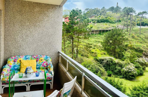 Colorida zona de estar en balcón con vistas a verdes colinas e Islas Cíes en Holibai, Baiona